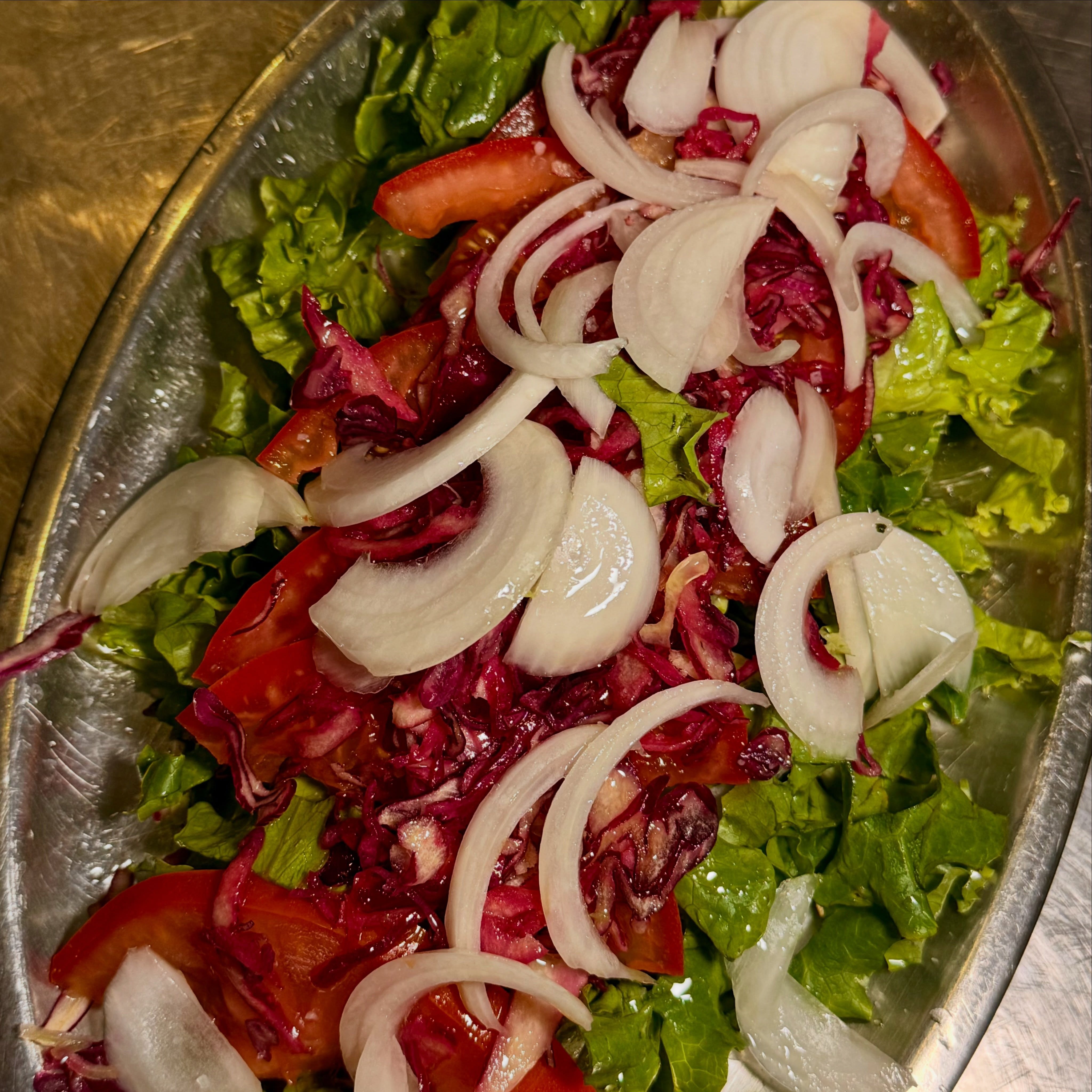 Salada mista numa travessa de alumínio com alface, tomate, cebola e radicchio