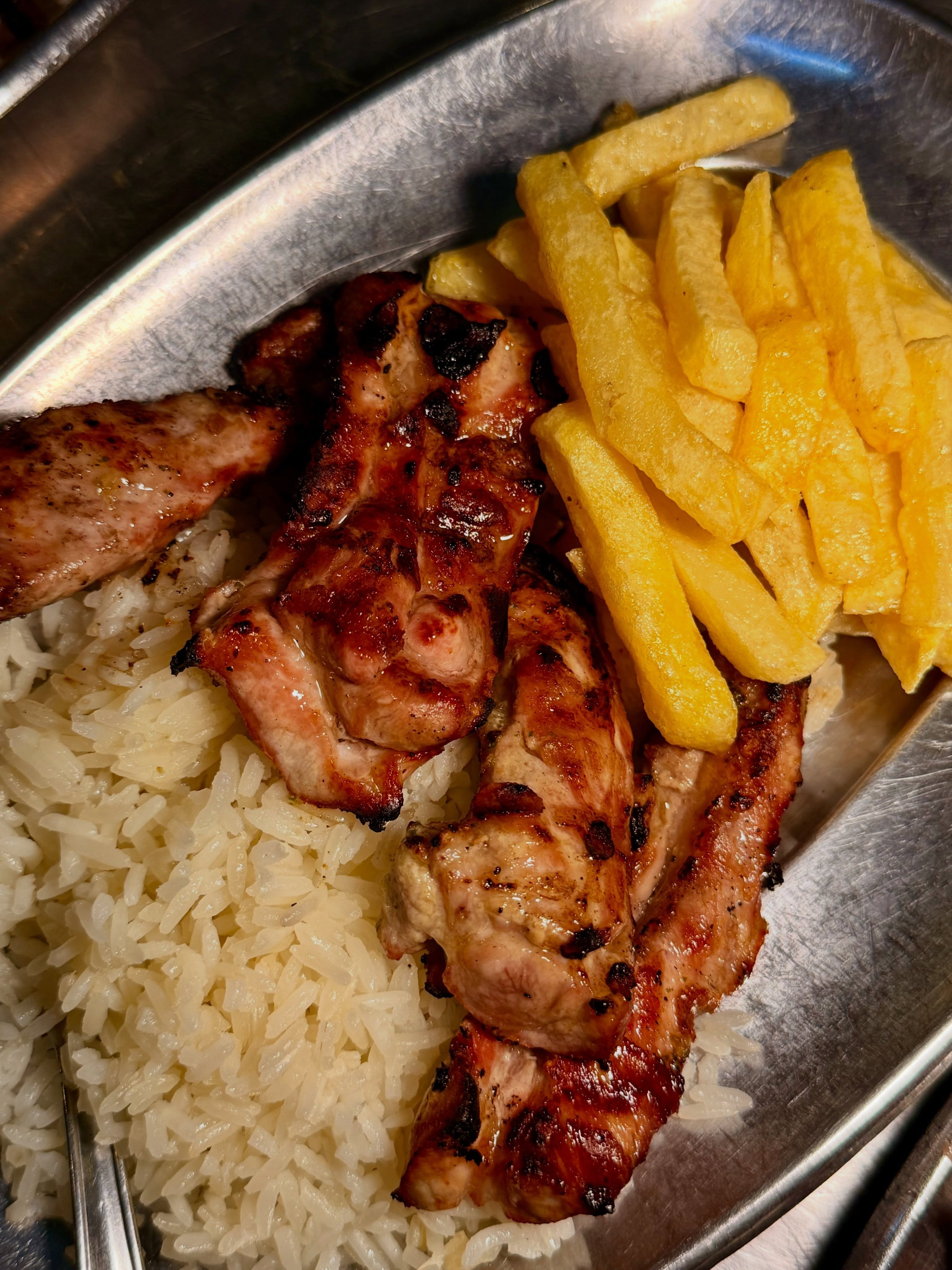 Peito de frango grelhado com arroz branco e batata frita numa travessa de metal